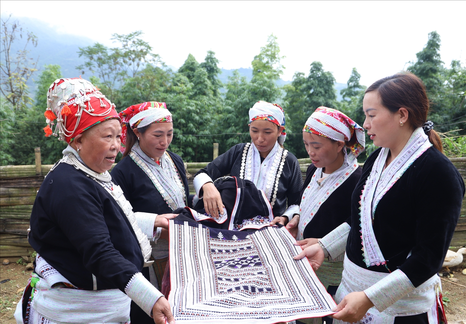 Nghệ nhân dân gian Tẩn Tả Mẩy (ngoài cùng bên trái) và chị em người Dao ở thôn Dền Sáng xem lại sản phẩm thổ cẩm do chính chị em thêu dệt nên