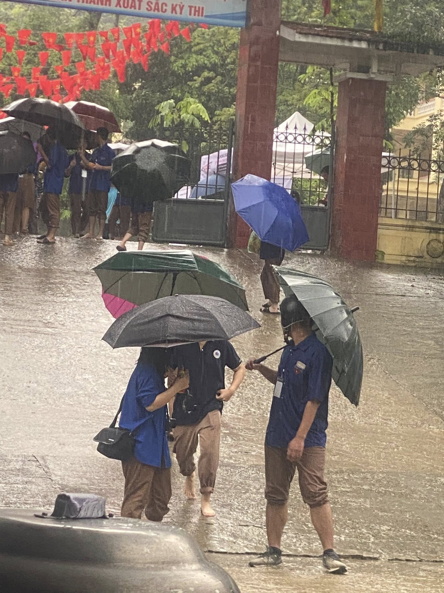 Xúc Động Giữa Mưa: Chiến Sĩ Áo Xanh Ướt Sũng Vẫn Cười, Tiếp Sức Cho 2K7 Vượt Vũ Môn! 1 Các bạn học sinh tình nguyện vẫn miệt mài đứng dưới mưa, áo quần ướt đẫm, đôi giày sũng nước