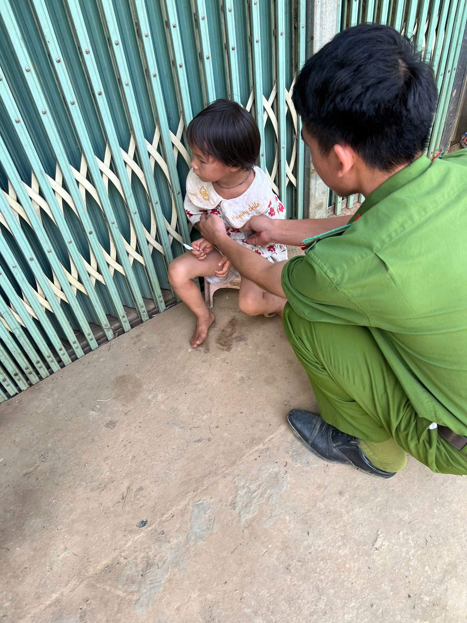 Phát hiện một bé gái nhỏ ngồi một mình trước cửa nhà trong tình trạng không có người thân đi cùng ( ảnh Công an xã Nậm Xé )