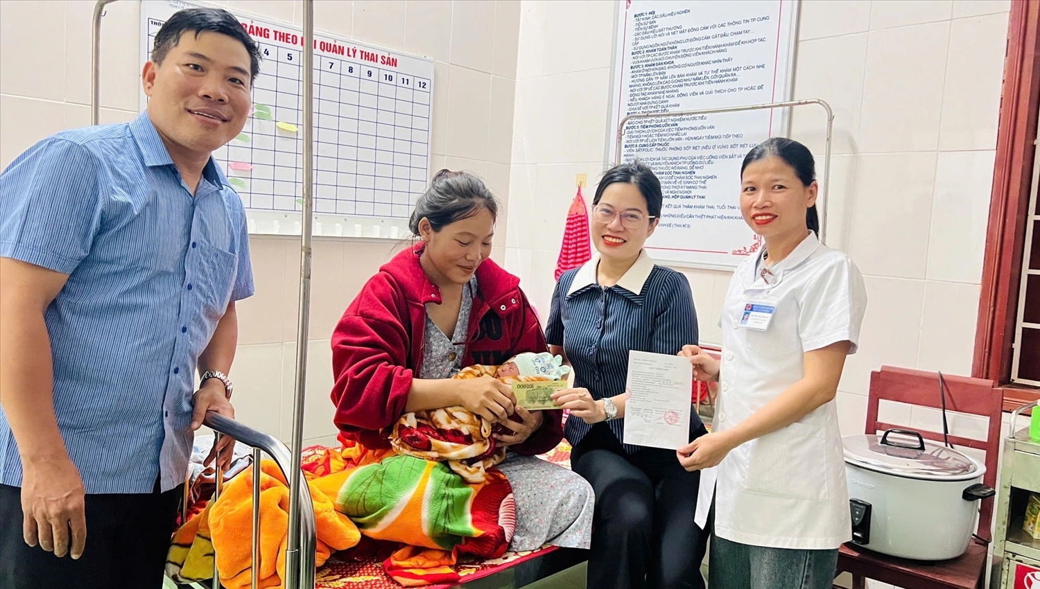 Đi nhận quà Quốc khánh, sản phụ người Bru Vân Kiều chuyển dạ sinh con 1 Bà Nguyễn Thị Hoài Ly (thứ 2 trái sang) trao món quà cho cháu Hồ Quốc Khánh - Ảnh: CSCC