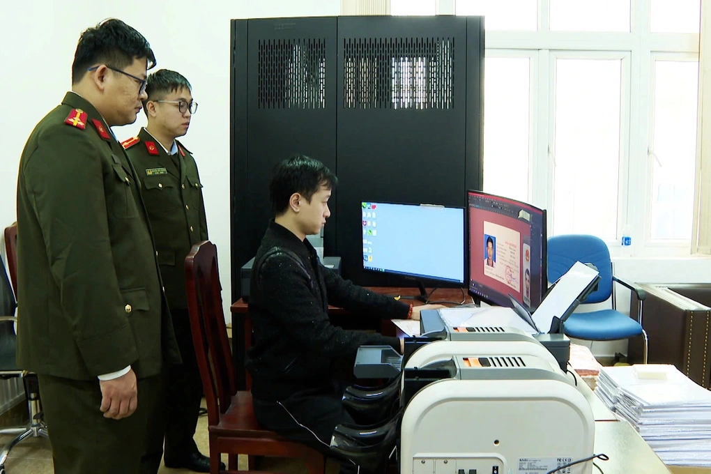 Cơ quan chức năng khám xét nơi sản xuất giấy tờ giả của đối tượng Phạm Duy Phú (ngồi máy tính), kẻ cầm đầu đường dây (Ảnh: Công an cung cấp).