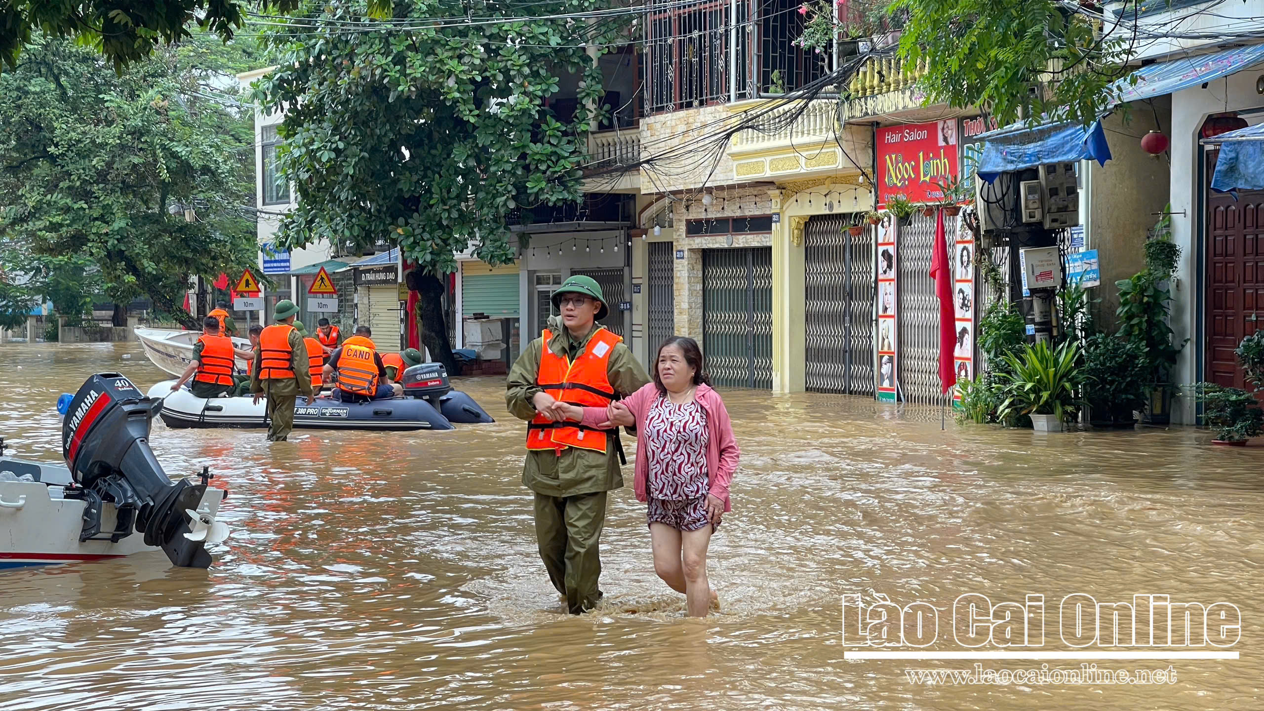 Cán bộ, chiến sĩ hỗ trợ người dân di chuyển an toàn qua vùng ngập sâu.