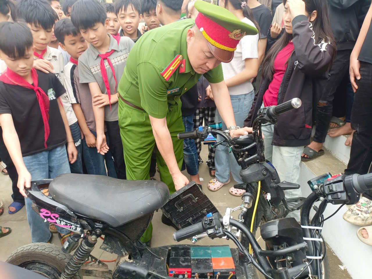 Cán bộ Công an xã Lâm Thượng trực tiếp kiểm tra hệ thống pin và các thiết bị lắp thêm trên xe đạp điện của học sinh trước sự chứng kiến của đông đảo học sinh và giáo viên.