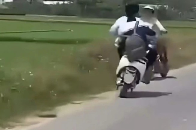 Hai thiếu niên điều khiển xe điện lạng lách, đánh võng trên một đoạn đường dài, bất ngờ tạt đầu rồi mất lái, trượt ngã và va chạm với người phụ nữ đang dừng xe bên đường. (Ảnh cắt từ clip)