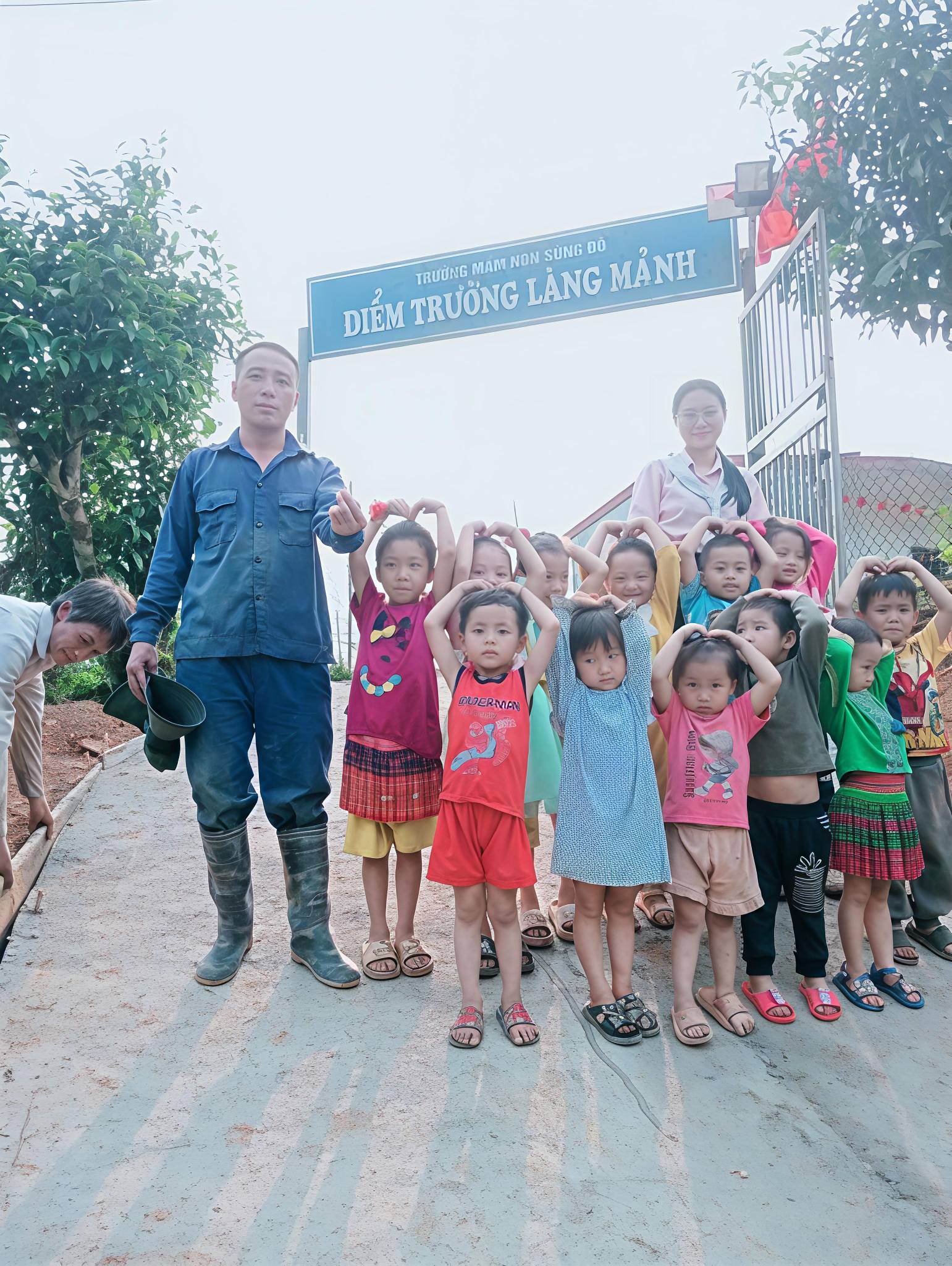 các em nhỏ chụp ảnh tại cổng điểm trường mầm non Làng Mảnh trên tuyến đường mới.