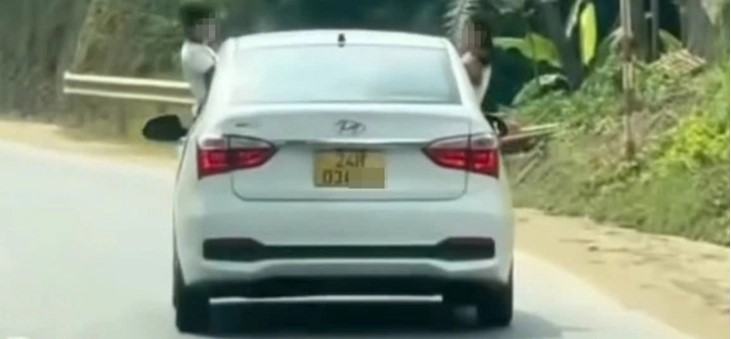 Hình ảnh trẻ đu bám, thò đầu ra khỏi cửa ô tô đang chạy - Ảnh: Công an cung cấp