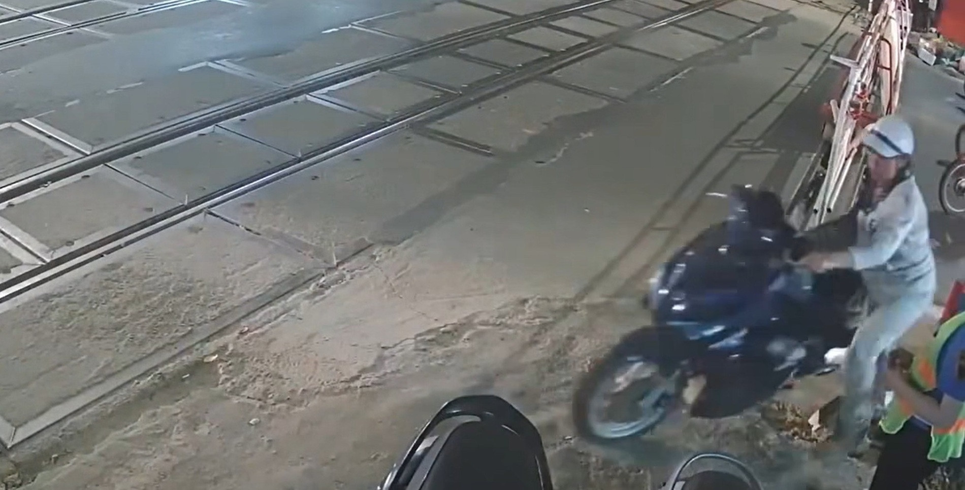Người phụ nữ dắt xe máy lách qua gác chắn. Ảnh: Cắt từ clip.