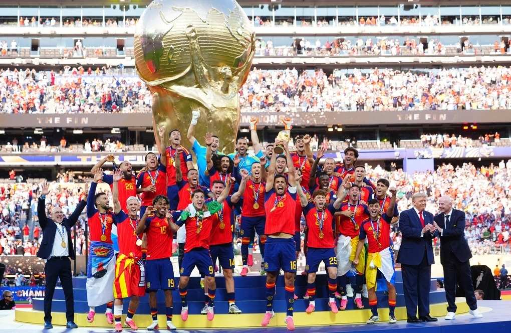 Chủ tịch FIFA nhiều lần ra hiệu, ông Trump vẫn đứng cạnh tuyển Tây Ban Nha khi nâng cúp vô địch 1 Tổng thống Mỹ Donald Trump và Chủ tịch FIFA Gianni Infantino (ngoài cùng bên phải) khi đội tuyển Tây Ban Nha nâng cúp vàng. Ảnh: AFP